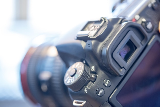 Le photographe tient un appareil photo reflex avec téléobjectif dans sa main Table et ordinateur portable dans l'arrière-plan flou