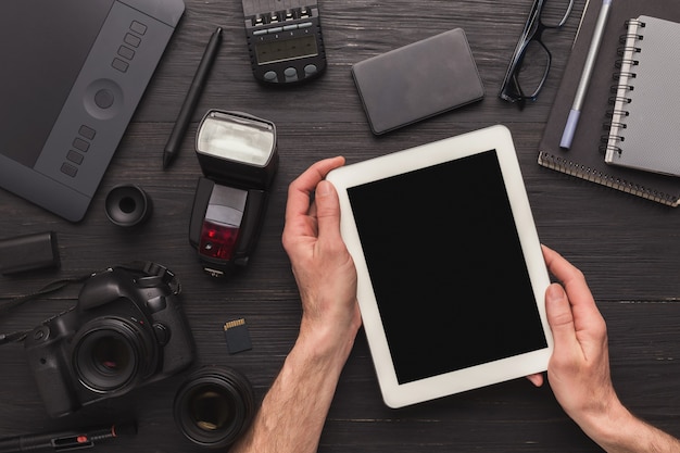 Photographe utilisant une tablette numérique vierge sur le lieu de travail avec équipement photo, défilement de photos, concept de technologie et de communication, vue de dessus, espace de copie