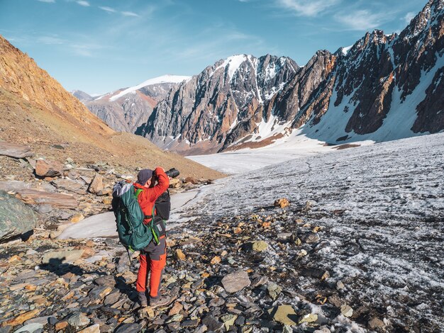 Le photographe de voyage prend une photo d'une vue magnifique dans les hautes montagnes enneigées. Mode de vie de blogueur indépendant de voyage, voyage d'aventure de concept en plein air.