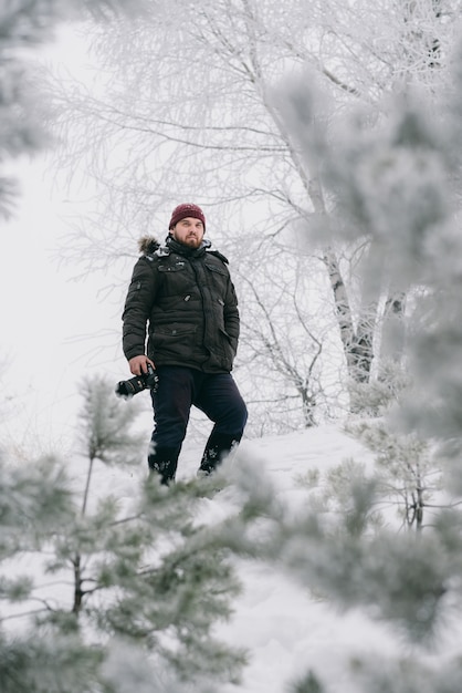 Photographe voyageur prenant des photos dans la forêt d'hiver