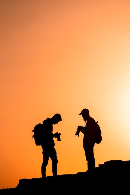 Photographes de silhouettes qui photographient un coucher de soleil dans les montagnes. Concept de photographe