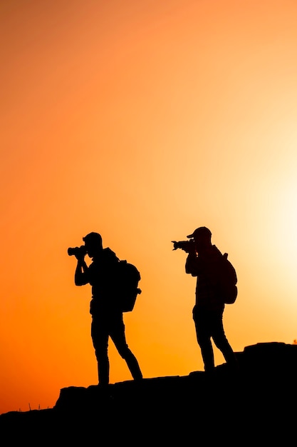 Photographes de silhouettes qui photographient un coucher de soleil dans les montagnes. Concept de photographe