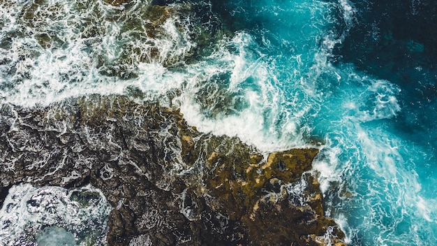 Photographie aérienne des vagues se brisant sur les rochers