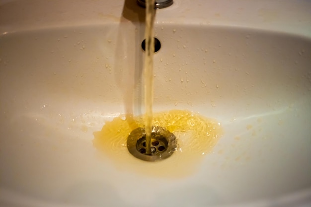 Photo photographie couleur d'une eau rouillée qui coule d'un robinet en gros plan eau sale du robinet