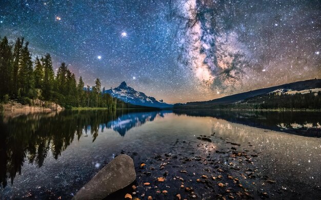 Photo photographie du lac la nuit avec des montagnes en arrière-plan et un ciel étoilé