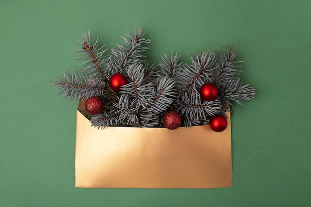 Photographie d'en haut d'une enveloppe dorée avec des branches d'arbres de Noël dedans