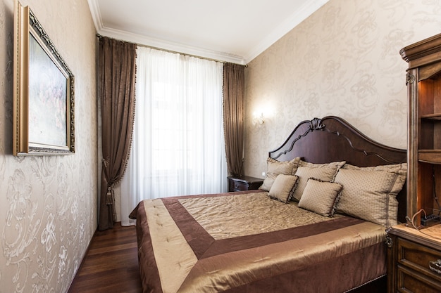 Photographie d'intérieur chambre de luxe avec grand lit en bois de style classique