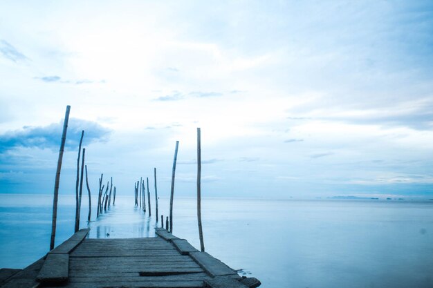 Photographie longue exposition d'un pont en bois dans la mer bleue