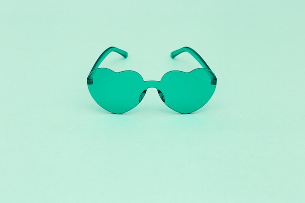 Photographie de mode de style minimal avec des lunettes en forme de coeur Lunettes de soleil modernes vert clair. Concept d'été.