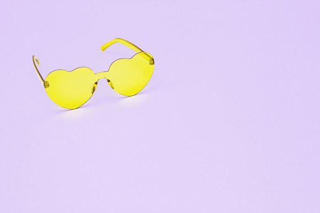 Photographie de mode de style minimal avec des lunettes en forme de coeur sur rose