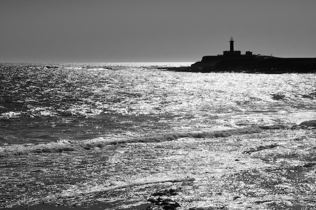 Photographie de silhouette d'un phare maritime en noir et blanc
