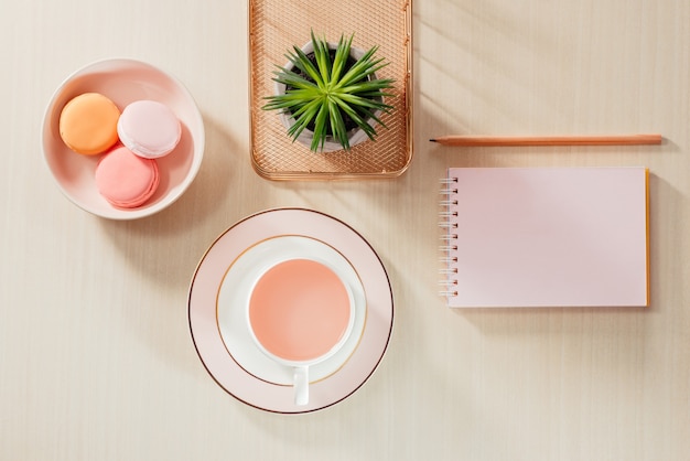 Photographie de stock de style table de bureau beige avec cahier vierge, macaron, fournitures et tasse à café