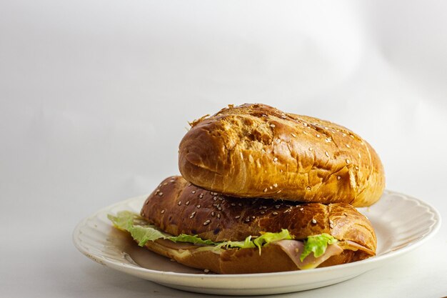 Photo photographie en studio d'un sandwich sur fond blanc avec du pain ouvert avec du fromage, du jambon, de la laitue et de la mayonnaise sur une assiette pour le petit déjeuner