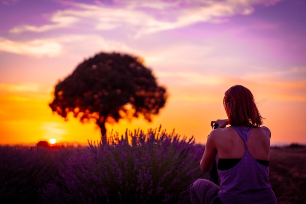 Photographies d'une femme au coucher du soleil dans un champ de lavande prenant une photo Brihuega Guadalajara Espagne