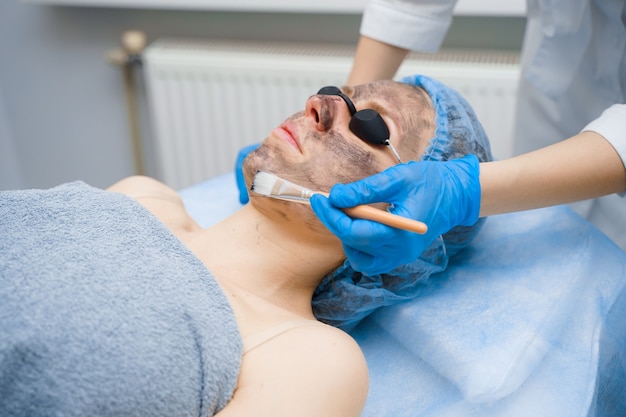 Photorajeunissement au laser et peeling au carbone du visage pour femme. Masque noir. Dermatologie et cosmétologie. Utilisation d'un laser chirurgical.