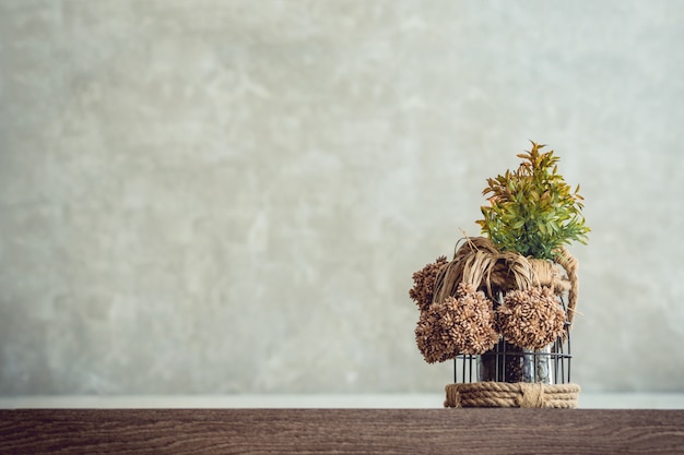 Photo photos de l'avant d'un pot de plantes ornementales posé sur une table en bois avec un fond de mur de ciment