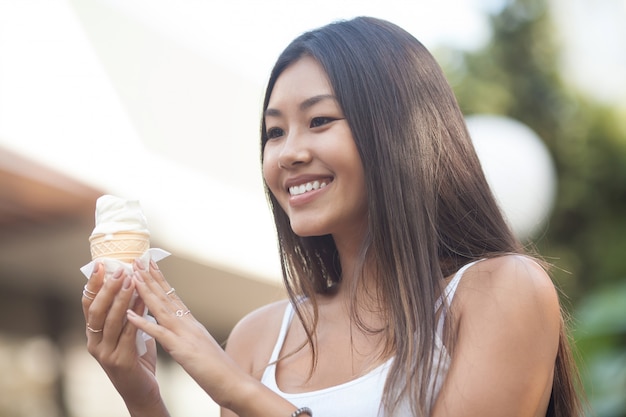 Photos de femme asiatique mangeant des glaces et debout par temps chaud. Le bonheur émotionnel. Concentrez-vous sur le visage.