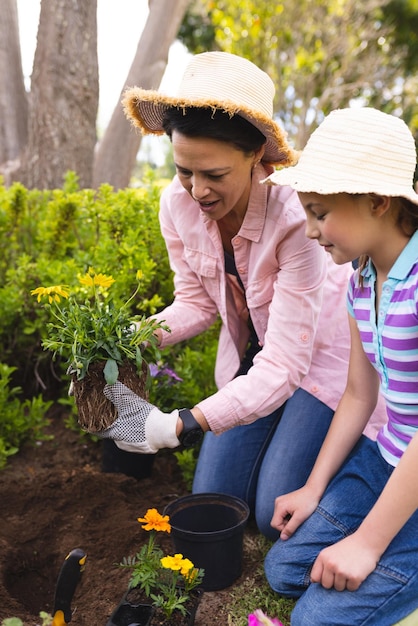 Photos verticales de la mère et de la fille caucasiennes passant du temps ensemble dans la plantation de jardin. Passer du temps en famille à l'extérieur, jardin, jardinage, concept.