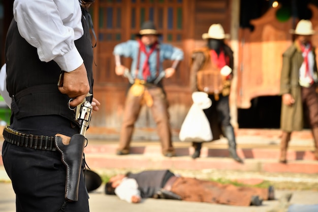 Photos vintage d'un shérif et d'un groupe de voleurs de cow-boys qui braquent une banque face à face. Tout le monde a une arme à la main, concentrez-vous sur le shérif.