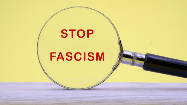 Phrase STOP FASCISM lettrage à travers une loupe sur un fond clair