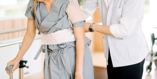 Physiothérapeute aidant une femme âgée avec une marchette à la gymnastique corrective