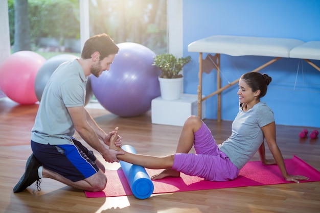 Physiothérapeute aidant la femme pendant l'exercice sur un tapis d'exercice