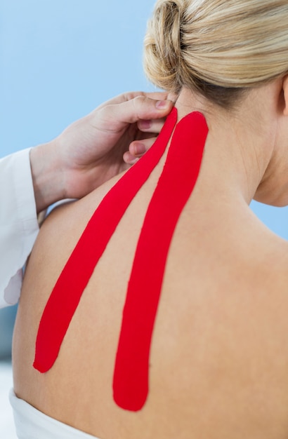 Physiothérapeute, coller du ruban adhésif sur une patiente