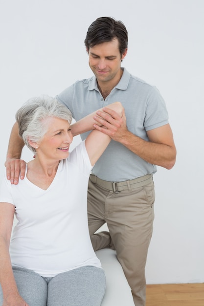 Physiothérapeute étirement d&#39;un bras womans senior souriant