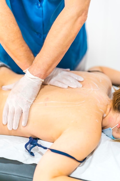 Physiothérapeute faisant un massage avec des gants sur le dos d'une jeune femme Réouverture avec mesures de sécurité en physiothérapie dans la pandémie de Covid19 Ostéopathie chiromassage thérapeutique