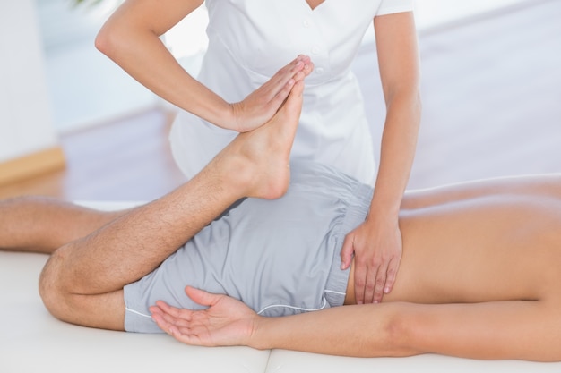 Physiothérapeute faisant massage des jambes à son patient