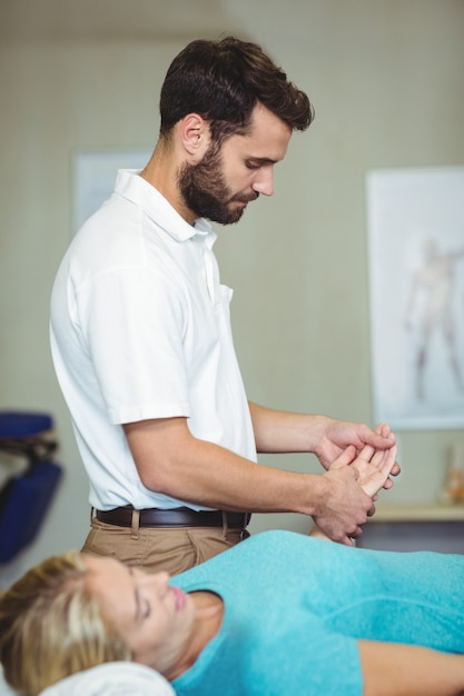 Physiothérapeute masculin donnant un massage des mains à une patiente