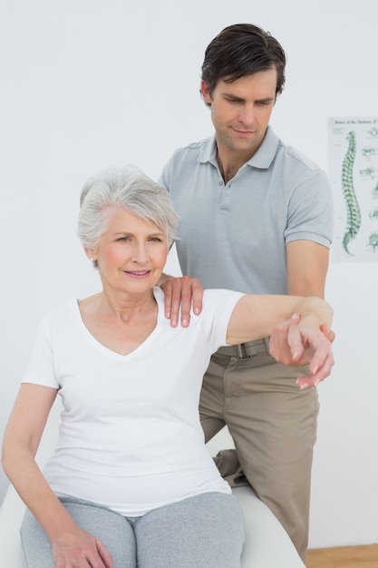 Physiothérapeute masculin étirement d&#39;un bras womans senior