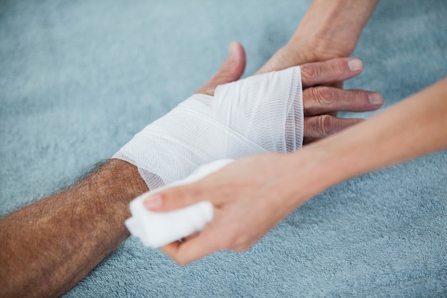 Photo physiothérapeute, mettre un bandage sur la main blessée du patient