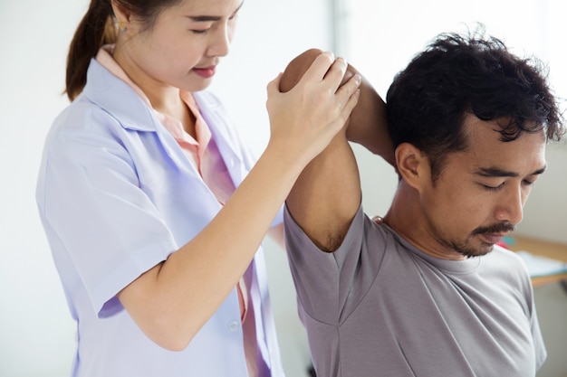 Physiothérapeute professionnelle donnant un massage de l'épaule à l'homme.