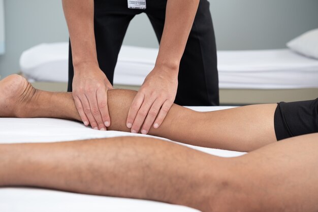 Les physiothérapeutes utilisent les poignées de la jambe du patient pour s&#39;allonger sur le lit dans une salle médicale.