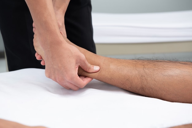 Les physiothérapeutes utilisent les poignées de la jambe du patient pour s&#39;allonger sur le lit dans une salle médicale.