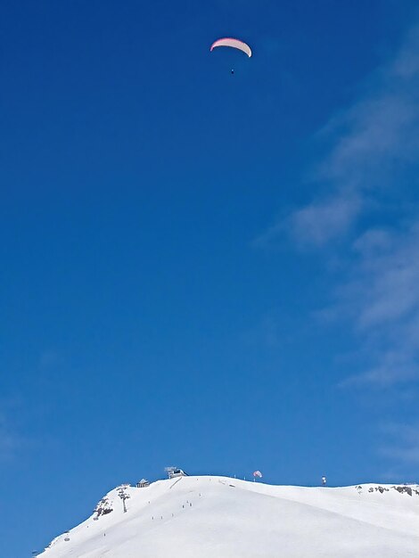Pic enneigé et ciel bleu avec des parachutistes