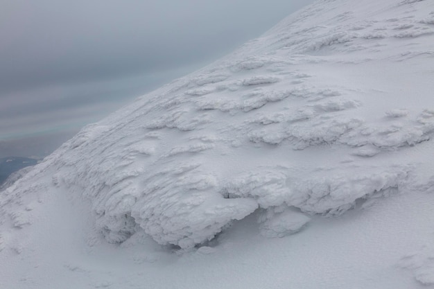 Pic de mont enneigé blanc le jour de la tempête dans les hautes montagnes