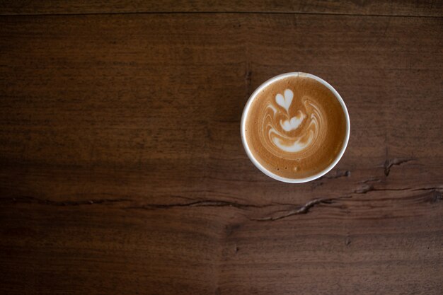 Piccolo Latte art dans une tasse en papier sur un bureau en bois