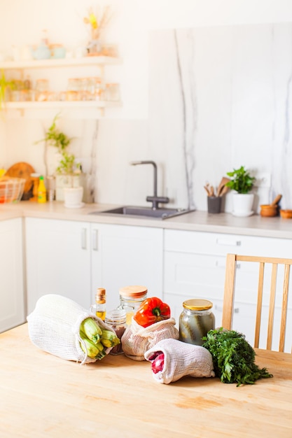 Épicerie dans des sacs textiles et des bocaux en verre posés sur la table de la cuisine après des achats zéro déchet