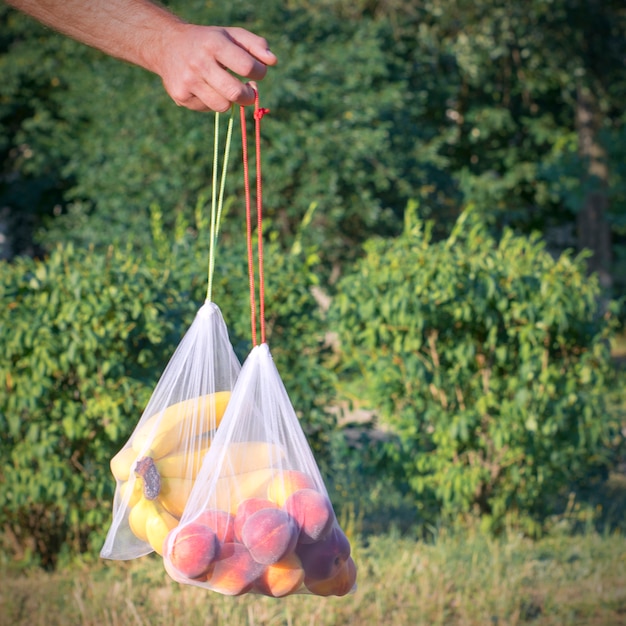 Épicerie maille avec des fruits à la main sur fond de nature