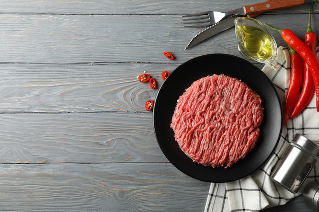 Épices et assiette de viande hachée sur bois, vue de dessus