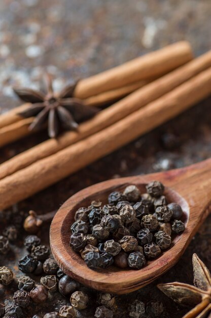 Épices et herbes. Ingrédients alimentaires et de cuisine. Bâtons de cannelle, étoiles d'anis, grains de poivre noir et cardamome sur une surface texturée.