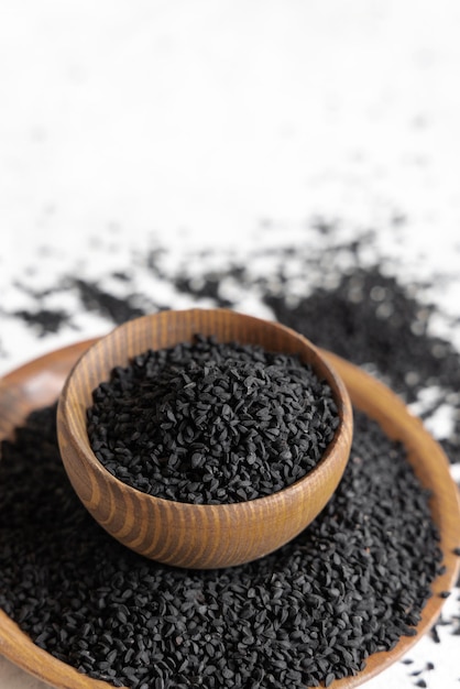 Épices indiennes Graines de cumin noir nigella sativa ou kalonji dans des bols en bois se bouchent avec espace de copie Médecine traditionnelle concept de nourriture saine et végétarienne