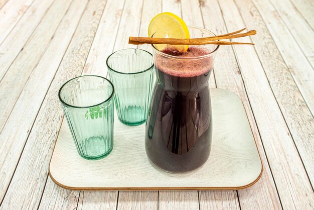 Pichet de chicha morada avec quartier de citron en bâton de cannelle et deux verres en cristal