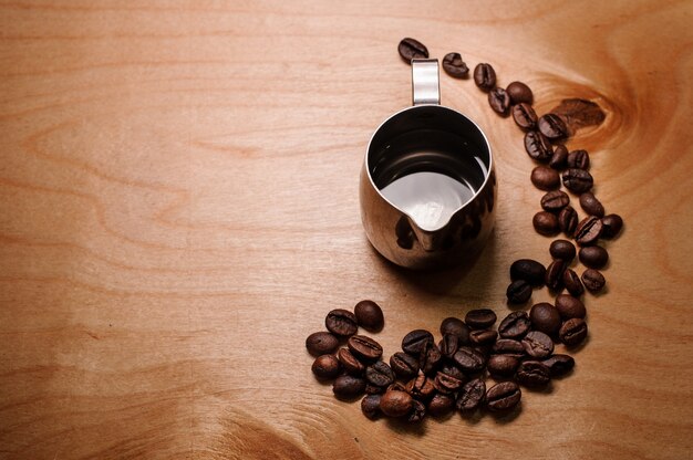 Pichet avec de l'eau parmi les grains de café frais