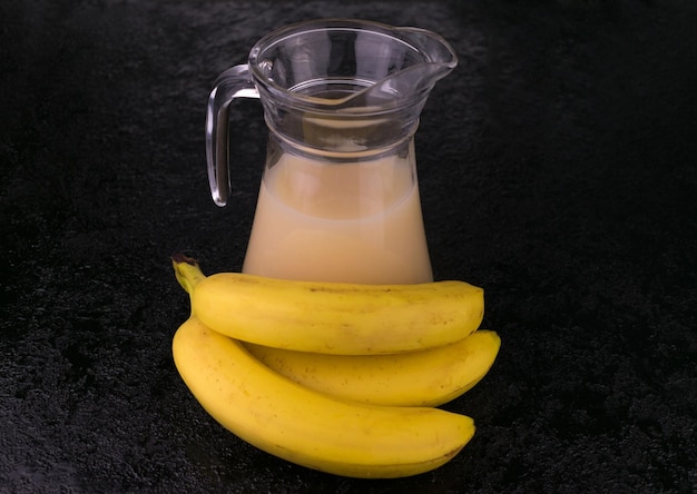 Un pichet de jus de banane sur fond noir Gros plan