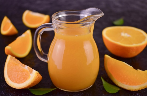 Un pichet de jus d'orange à côté d'une moitié d'oranges.