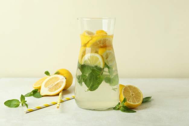 Pichet de limonade, citrons et pailles sur table texturée blanche