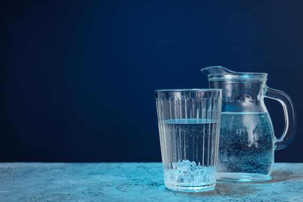 Pichet et verre d'eau sur fond texturé bleu